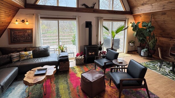 A cozy loft-style living room with a fireplace, leather furniture, and large windows offering views of the outdoors. - 474, Your Mountain Getaway. (Keyser)