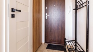 A hallway with a wooden door, a metal coat rack, and a doormat.