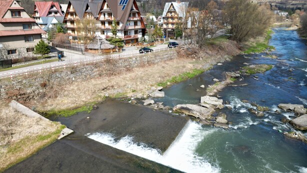 Een rij traditionele chalets met een rivier ernaast.