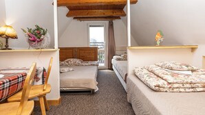A cozy attic bedroom with two beds, a wooden ceiling, a desk with a lamp, and a window with a view. - Mountain Spirit Dream Studio (Zakopane)