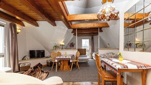 A cozy attic bedroom with a wooden ceiling, a dining table, and a bed. - Mountain Spirit Dream Studio (Zakopane)