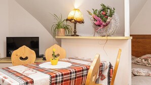 A cozy living room with a plaid tablecloth, a wooden chair, a lamp, a potted plant, and a decorative nest with flowers. - Mountain Spirit Dream Studio (Zakopane)
