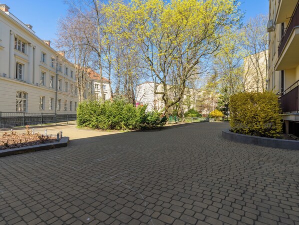 Un patio empedrado con edificios a ambos lados, cielo despejado y árboles con hojas amarillas.