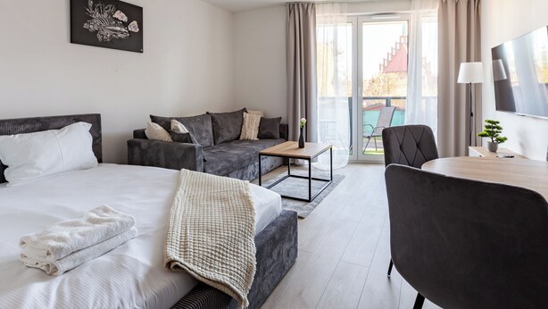 Une chambre d’hôtel avec un lit, un canapé, une table et un téléviseur.
