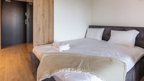 Une chambre d’hôtel moderne avec un grand lit, des panneaux de bois et une palette de couleurs neutres.