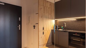 Une cuisine moderne avec des meubles en bois, un plan de travail noir et un four encastré.