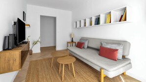 A modern living room with a grey sofa, red and grey cushions, a wooden coffee table, a TV on a wooden stand, and a bookshelf with books. - Warszawa Rakowiec Stylish Apartment (Warszawa)