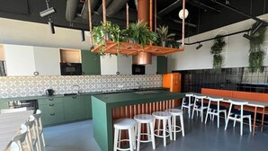 Una cocina moderna con gabinetes verdes, una isla central y plantas colgantes.