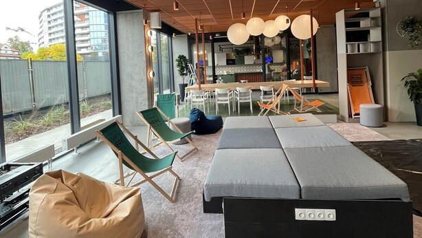 Ein modernes Interieur mit großem Fenster, einer Sitzecke und einer Küche im Hintergrund.