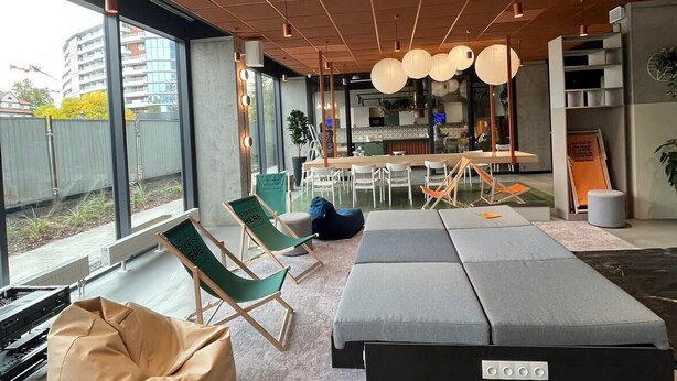 A modern interior with a large window, seating area, and a kitchen in the background. - Chillout Dorm Cracow (Kraków)