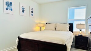 A bedroom with a large bed, two bedside tables with lamps, and three wall-mounted artworks. - Cozy and Charming House (Pineville)