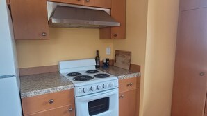 A kitchen with wooden cabinets, a white stove, and a beige wall. - The Nest in South Eugene (Eugene)
