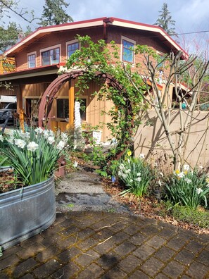 A two-story house with a red roof, brick exterior, and a wooden porch. - The Nest in South Eugene (Eugene)