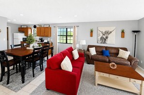 Un salon moderne avec un canapé rouge, un divan en cuir marron et une table basse en bois.