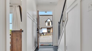 A hallway with a wooden door, a rug, and a view of a house with a garage. - Dolly-Themed 3BR Luxury Retreat w/ Arcade, Hot Tub & Lanai – Near Dollywood (Sevierville)