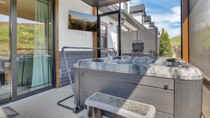 A modern outdoor hot tub with a metal frame and bench, set against a backdrop of a wooden deck and a scenic view of mountains and trees. - Dolly-Themed 3BR Luxury Retreat w/ Arcade, Hot Tub & Lanai – Near Dollywood (Sevierville)