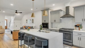 A modern kitchen with a central island, stainless steel appliances, and pendant lighting. - Dolly-Themed 3BR Luxury Retreat w/ Arcade, Hot Tub & Lanai – Near Dollywood (Sevierville)