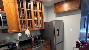 A modern kitchen with wooden cabinets, stainless steel appliances, and a patterned rug.