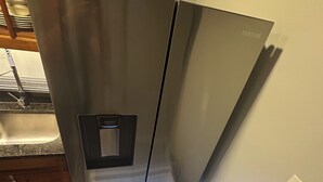 A stainless steel refrigerator with a built-in ice maker, a microwave, and a freezer compartment.