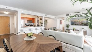 Una sala de estar moderna con comedor, sofá blanco y una planta grande.