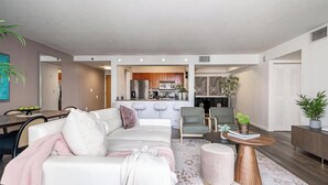 Una sala moderna con un sofá, sillones, una mesa de centro y un comedor con una mesa y sillas.