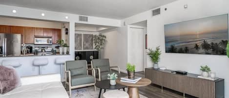 A modern living room with a sofa, armchairs, a coffee table, and a TV wall.