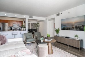 A modern living room with a sofa, armchairs, a coffee table, and a TV wall.