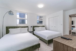 Ein Zimmer mit zwei Betten, einem Schreibtisch und einer Lampe.