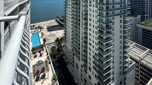 Un hotel de gran altura con múltiples balcones con vistas a una playa y una piscina.