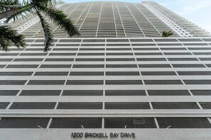 En høj bygning med et vinduesmønster og et skilt, der viser '1200 Brickell Bay Drive'.