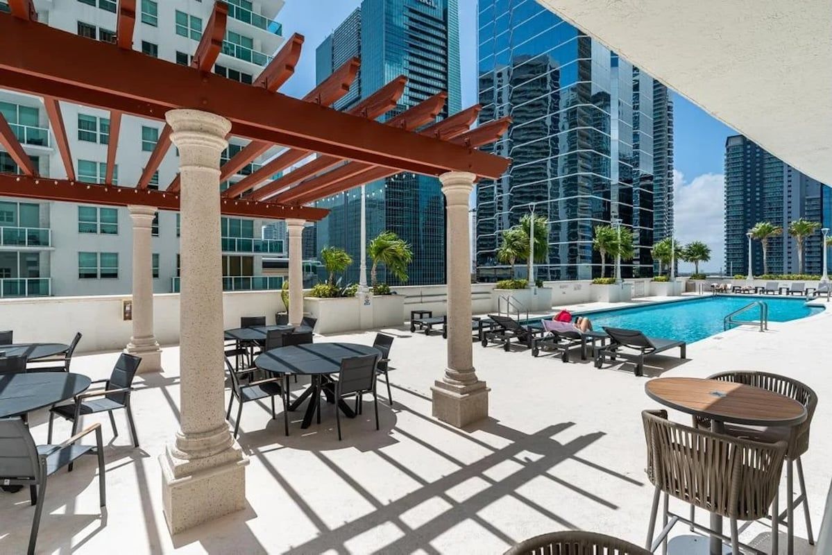 An outdoor pool area with tables and chairs, surrounded by high-rise buildings.
