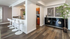 Una cocina moderna con una isla central, taburetes de bar y un mueble negro con pomos redondos.