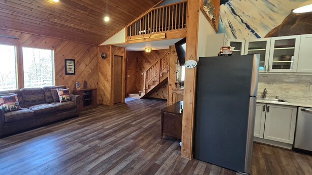 Un intérieur en bois comprenant un espace de vie, une cuisine et un escalier menant à une mezzanine.