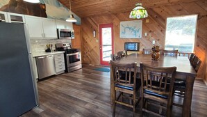 Une cuisine de style rustique, avec des murs en bois, un coin repas doté de chaises en bois et une grande fenêtre.