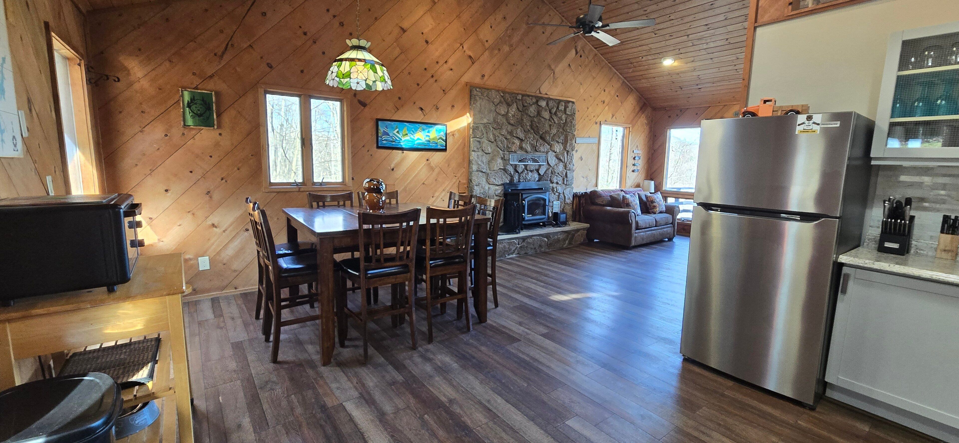 A cozy cabin interior with a dining area, living room, and kitchen.