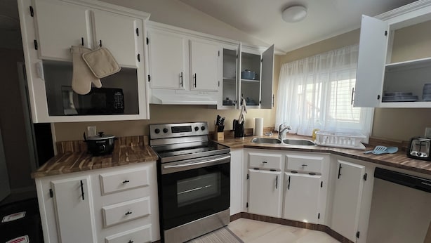 A modern kitchen with white cabinets, a stainless steel stove, and a wooden countertop. - 3 bedroom, 2 bathroom across from Walmart, 5 minutes to the airport & hospital. (Yellowknife)