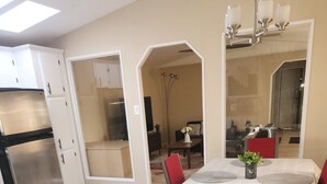 A modern kitchen with a built-in oven, a dining area with a table and chairs, and a large mirror above the table. - 3 bedroom, 2 bathroom across from Walmart, 5 minutes to the airport & hospital. (Yellowknife)