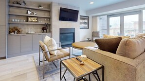 A modern living room with a fireplace, comfortable seating, and a TV mounted on the wall.