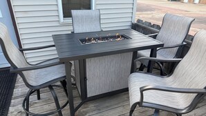 An outdoor patio with a table and four chairs, a fire pit, and a view of a building in the background. - The Bohemian Bungalow  near Main Street in Scenic Verdigre, Nebraska (Verdigre)