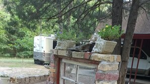 A rustic stone wall with a window, surrounded by a garden with plants and a small brick pathway. - 2 Cabins 1 Price Themed Cabins 2 Miles from Trade Days (Canton)