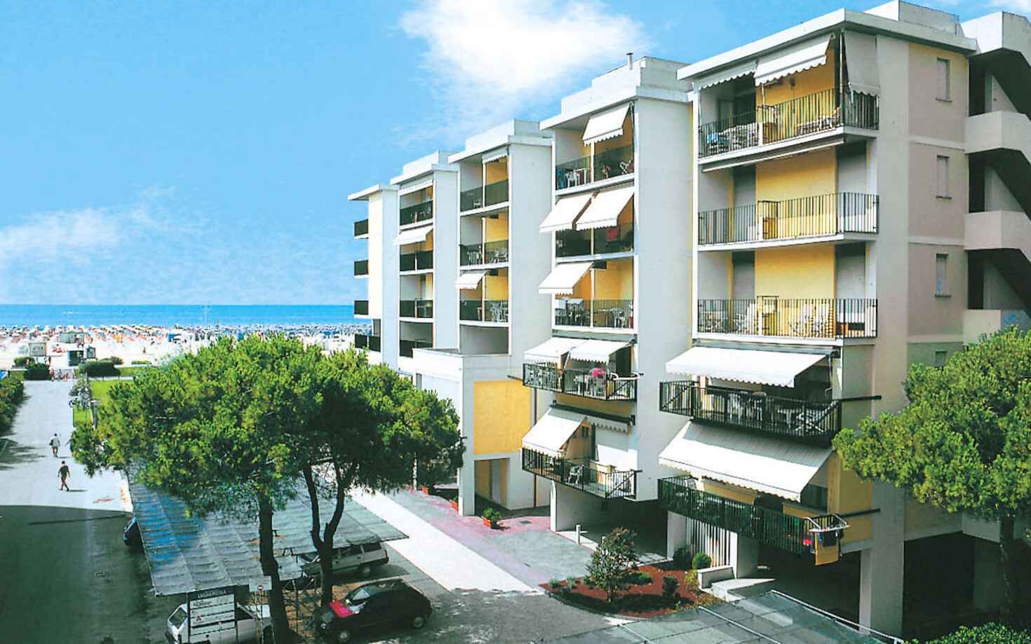 A multi-story hotel with balconies, a beach view, and a parking area.
