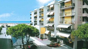 A multi-story hotel with balconies, a beach view, and a parking area.