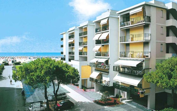 A multi-story hotel with balconies, a beach view, and a parking area.