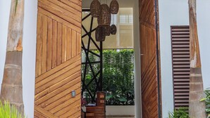 Una entrada moderna amb panells de fusta, un llum penjant i una escala que condueix a una zona coberta amb plantes.