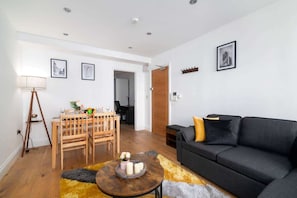 A modern living room with a black sofa, wooden dining table, and a coffee table.