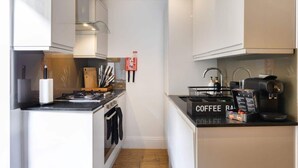 A compact kitchen with a coffee station, a stove, and a sink. - Stylish Brick Lane Apartment with Balcony Sleeps 4 (Greater London)