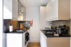 Cocina compacta con estación de café, estufa y lavamanos.