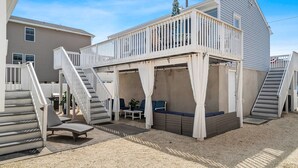 A two-story house with a balcony, a covered patio area, and a staircase leading to the upper level. - Beach House 2 Blocks to Beach Free Beach Badges, Towels & Parking (Seaside Heights)