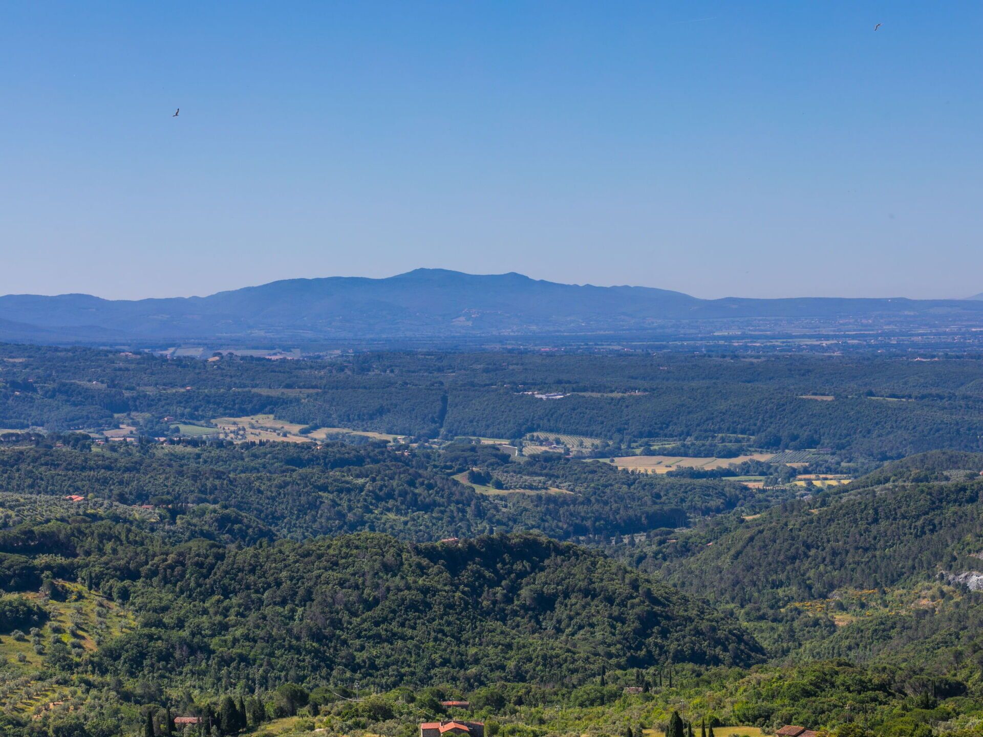 Ein weiter Panoramablick auf eine gebirgige Landschaft mit verstreuten Gebäuden.