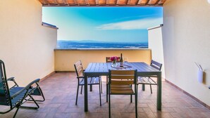 A patio with a table and chairs, a view of the sea, and a wooden ceiling. - Nice apartment for 4 guests with pool, A/C, WIFI, TV, terrace and panoramic view (Riparbella)